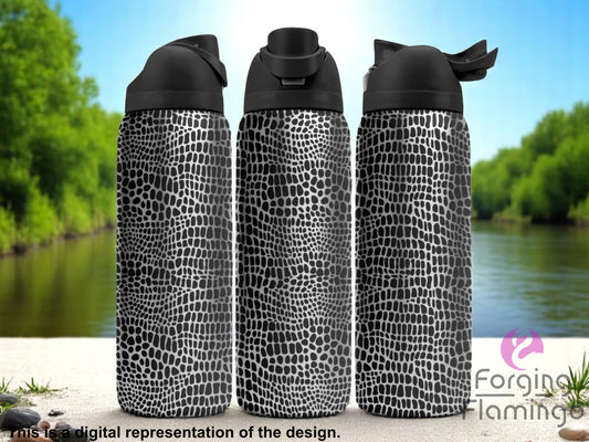 Three black tumblers with flip-top lids, engraved with an all-over reptile or scaled texture pattern, displayed outdoors on a dock by a river with green trees and a blue sky in the background. Text below reads “This is a digital representation of the design.”