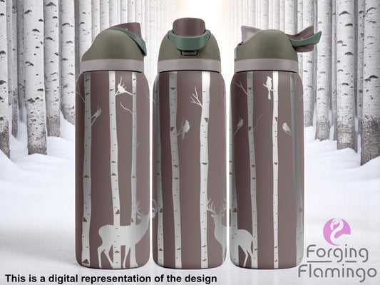 Three stainless steel tumblers with olive and taupe flip-top lids, engraved with a woodland scene of slender birch trees, perched birds, and deer silhouettes. The background features a snowy birch forest, creating a wintry, nature-inspired aesthetic. Text below reads “This is a digital representation of the design.”