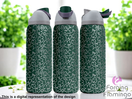 Three dark green Owala tumblers with a full-wrap laser-engraved shamrock pattern in various sizes, displayed indoors with bright natural light and leafy green plants in the background. Forging Flamingo logo appears in the bottom right corner.