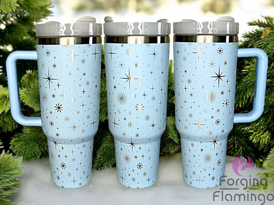 Composite image of a single light blue tumbler with a stainless base, engraved with Forging Flamingo's Stars & Snowflakes design, shown from multiple angles to showcase retro starbursts and delicate snowflakes in a seamless winter-themed wrap.
