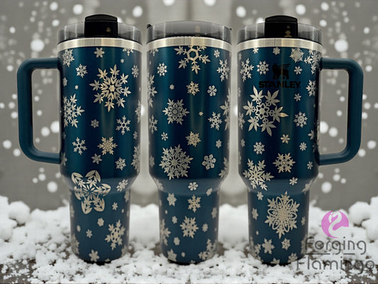 Three blue tumblers with snowflake patterns on a snowy background