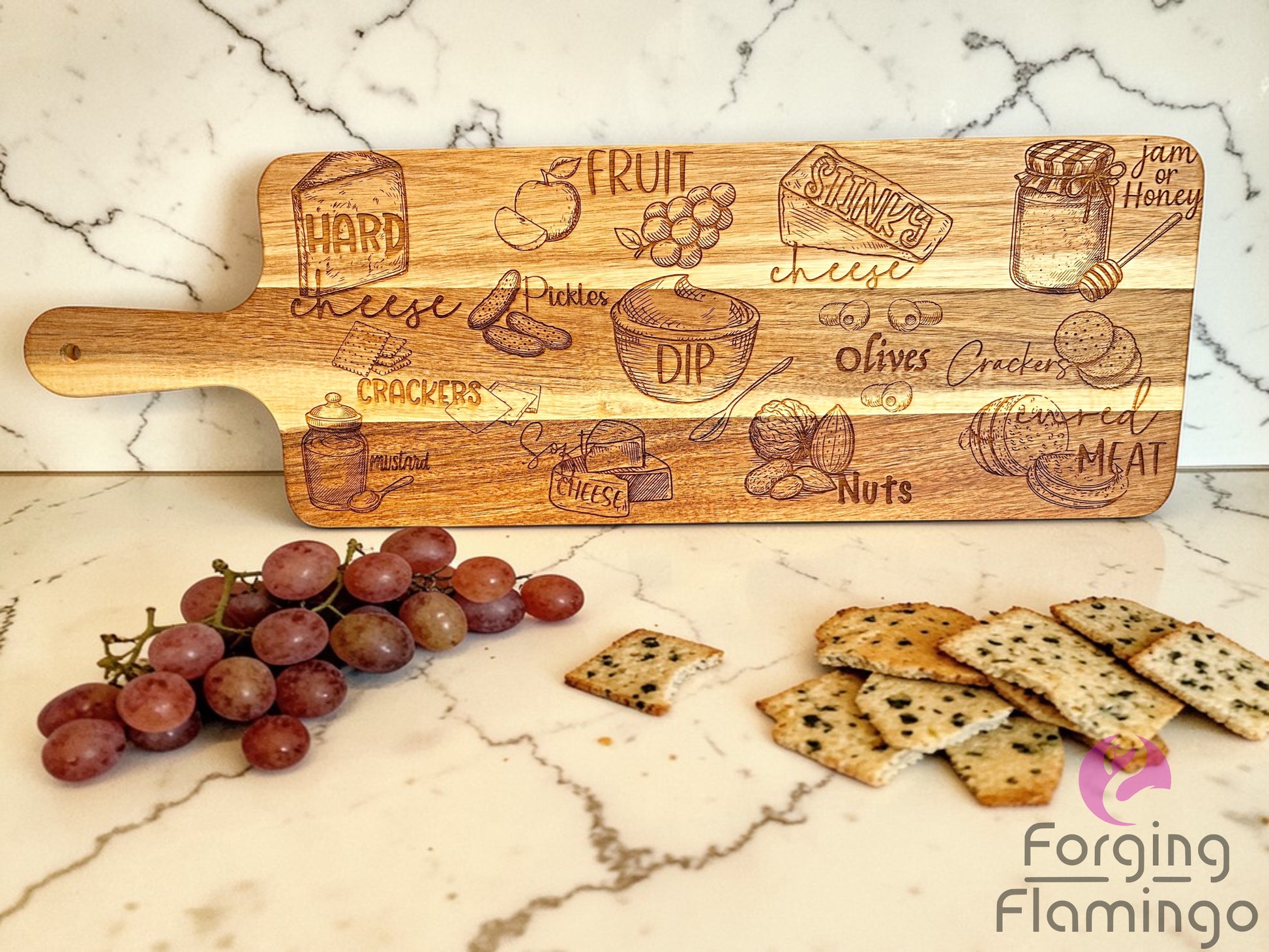 Wooden serving board with engraved food illustrations on a marble surface with grapes and crackers.