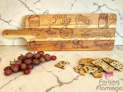 Wooden serving board with engraved food illustrations on a marble surface with grapes and crackers.