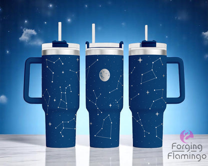 Three blue handled tumblers with white straw lids, displayed on a white marble surface against a starry night sky background. The tumblers feature a laser-engraved constellation design in silver metal, with various star patterns and a full moon illustration in the center tumbler. The engraving wraps around the cups, giving the appearance of a night sky filled with constellations. The Forging Flamingo logo appears in the lower right corner.
