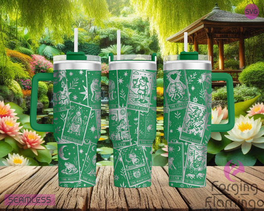 Three green stainless steel tumblers featuring a seamless laser-engraved Frog Tarot card design, displayed in front of a serene garden scene with lily pads, lotus flowers, and a wooden gazebo.