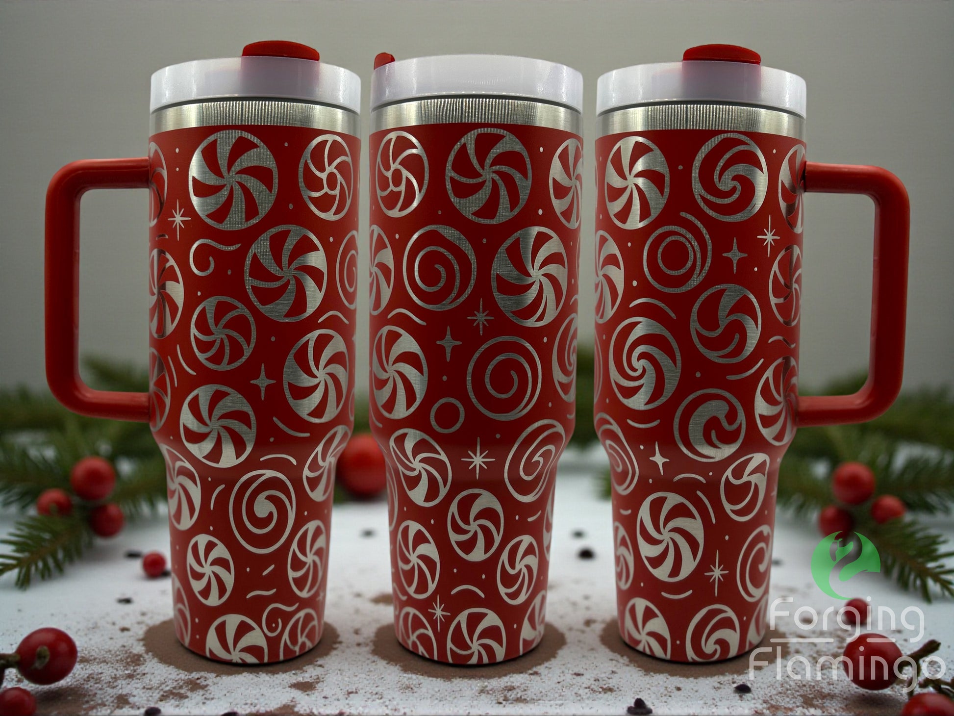 Three red travel mugs with candy cane patterns on a surface with Christmas decorations.