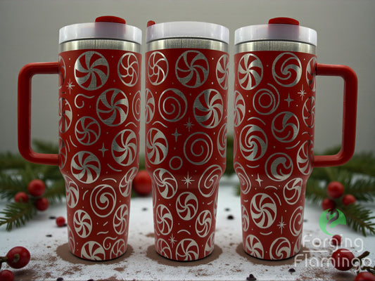 Three red travel mugs with candy cane patterns on a surface with Christmas decorations.