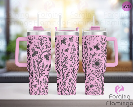 Three pink tumblers engraved with a seamless wildflower and bee design, shown on a counter with a softly blurred window and indoor-outdoor background.
