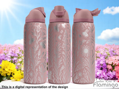 Three mauve pink Owala tumblers with laser-engraved wildflower and bee illustrations, featuring delicate stems, blossoms, and buzzing insects. Displayed outdoors with a bright blue sky and colorful flower field in the background. Forging Flamingo logo appears in the bottom right corner.
