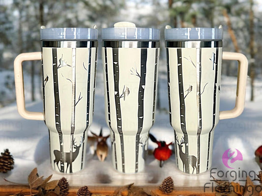 Composite image of a single Stanley tumbler engraved with Forging Flamingo's Birch Trees & Cardinals design, shown from multiple angles to highlight a peaceful forest scene with tall birch trees and perched cardinals in a seamless winter wrap.