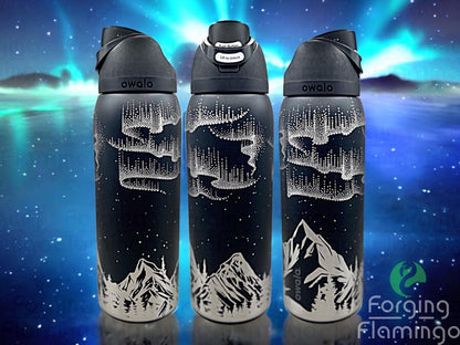 Composite image of a single Owala tumbler engraved with Forging Flamingo's Northern Lights with Mountains design, shown from multiple angles to showcase glowing aurora patterns above silhouetted mountain peaks in a seamless wrap.