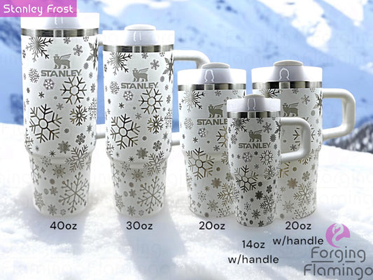 Composite image showing multiple white Stanley tumblers in different sizes, each engraved with Forging Flamingo's Snowflakes design. Displayed from various angles to showcase delicate, wintry snowflakes wrapped seamlessly around the cups.